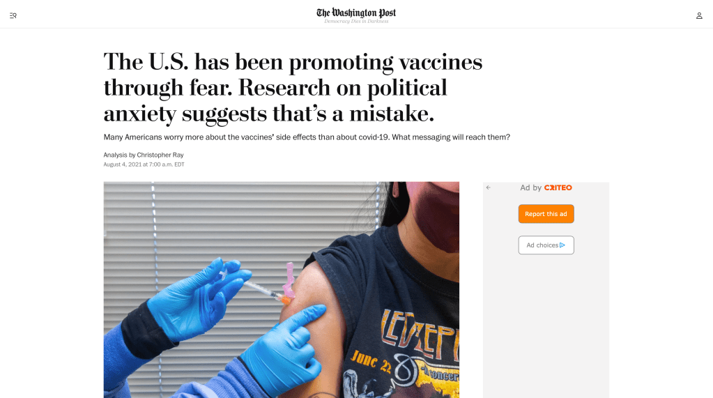 Screenshot of Washington Post headline and article by Christopher Ray. Headline says "The U.S. has been promoting vaccines through fear. Research on political anxiety suggests that’s a mistake." above a photo of a medical provider wearing blue latex gloves and administering a Covid-19 vaccine to a person wearing a cloth mask and a Led Zeppelin t-shirt.